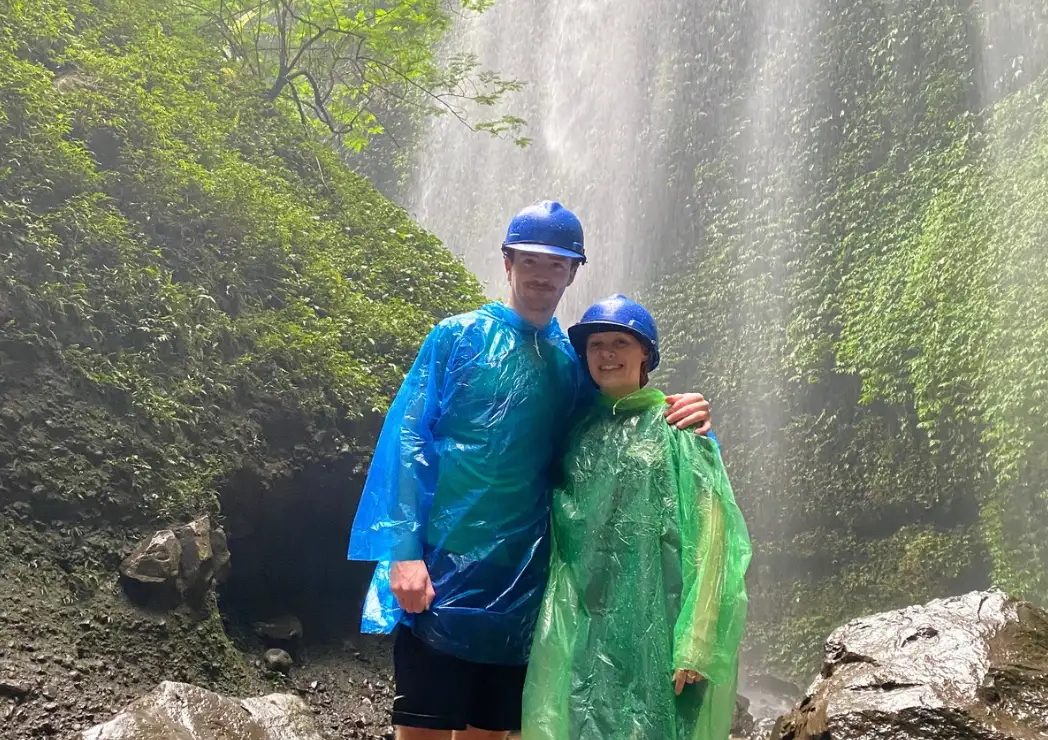 Tourists wearing raincoat and safety helmet at Madakaripura Waterfall.
